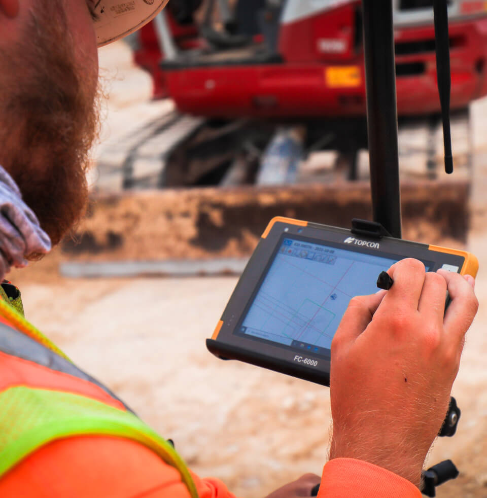 Man using a stylus on a tablet on a job site.
