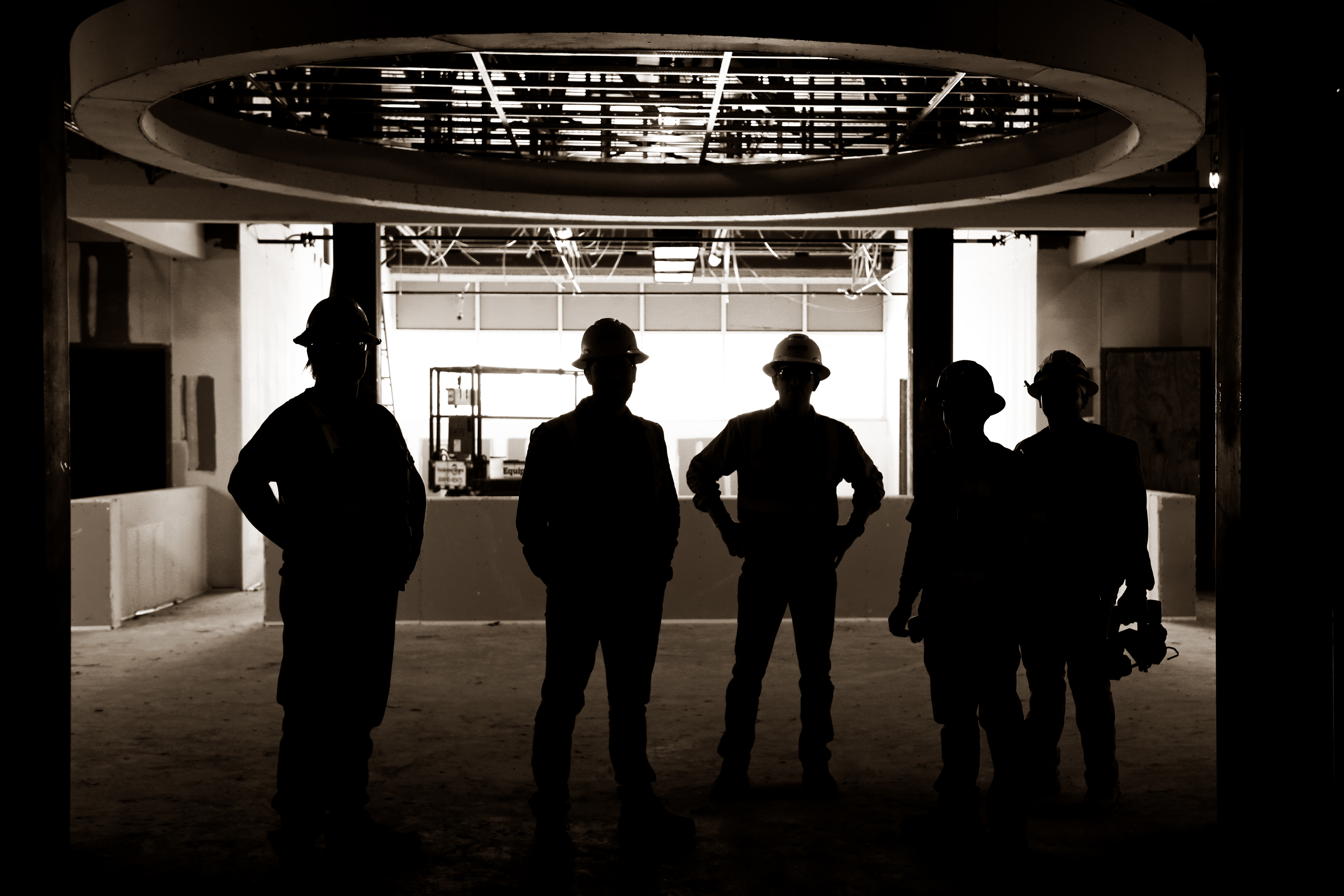 construction crew standing in a dark area in a building under construction